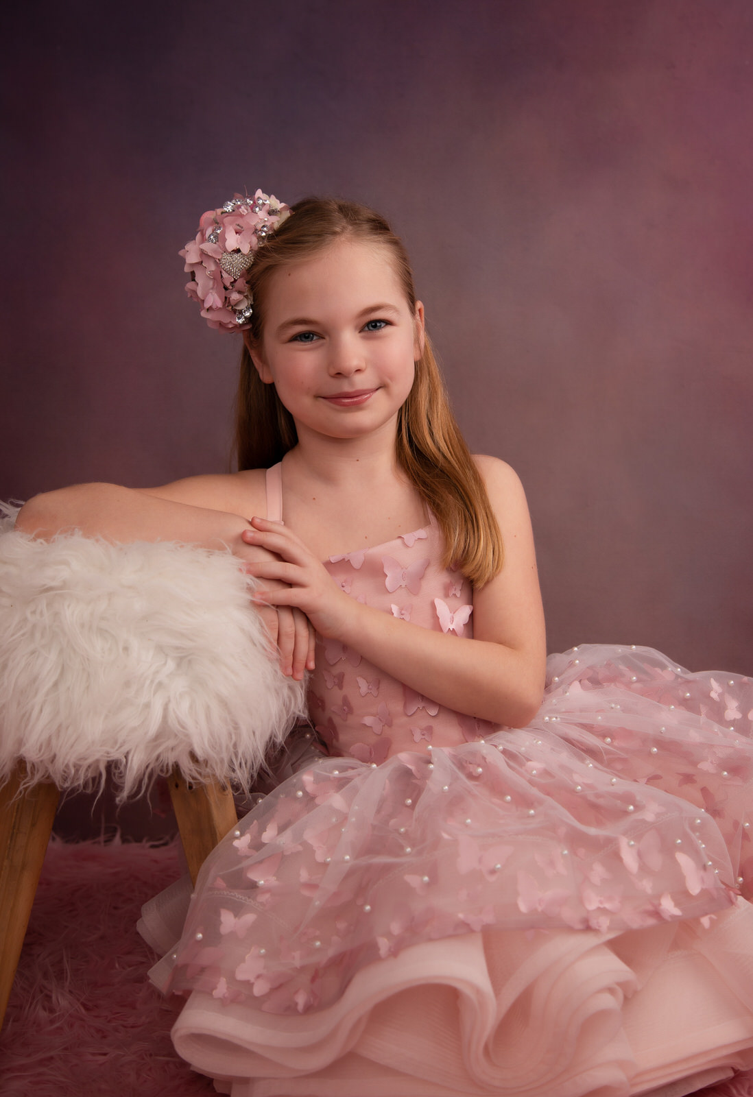 A young girl in a pink tutu dress leans against a fur covered stool DFW Kids
