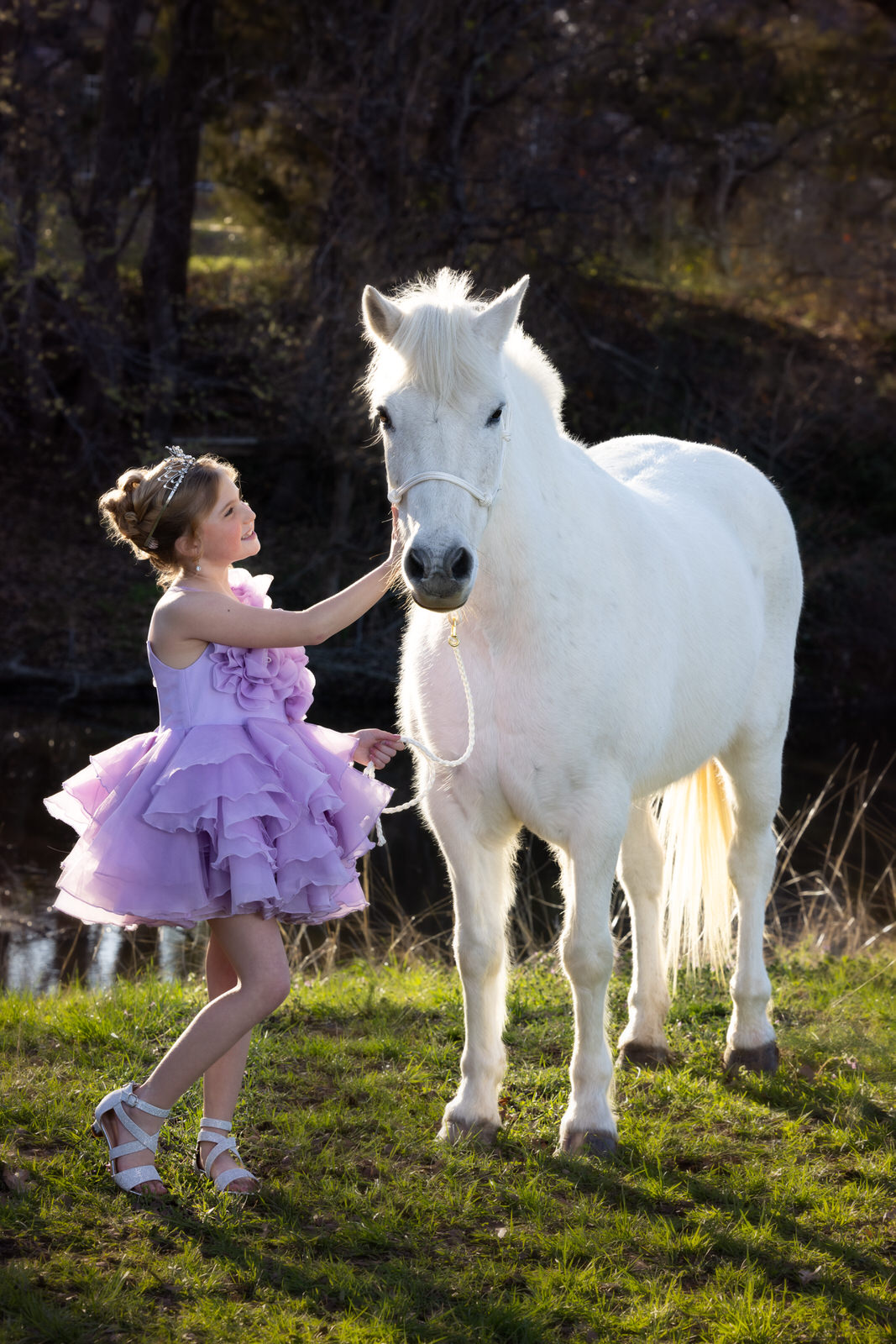 A young girl in a purple tutu pets a white horse next to a river things to do in dfw with kids