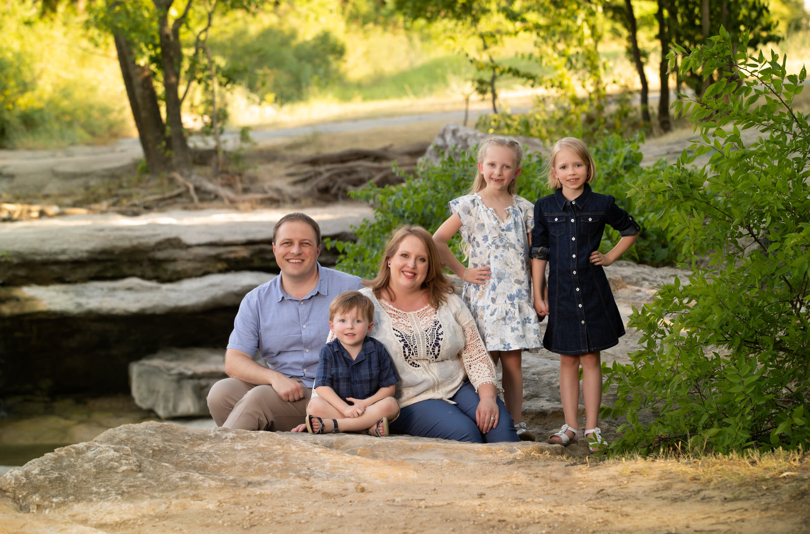 A family of five sits on a rock next to a river