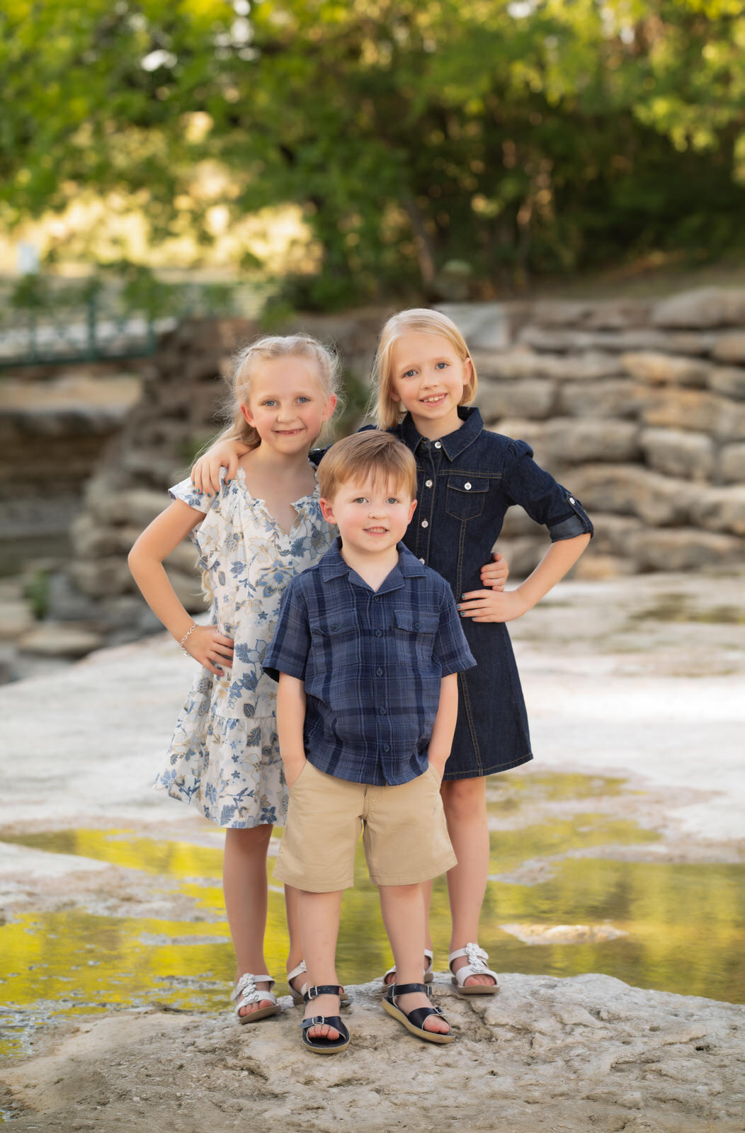 Three siblings stand on a rock next to a river with arms around each other things to do in fort worth with kids