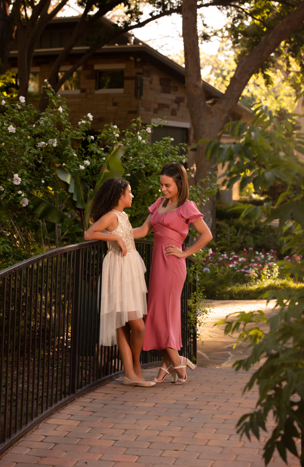 Two young women lean against a railing on a bridge, chatting in dresses things to do in mansfield tx
