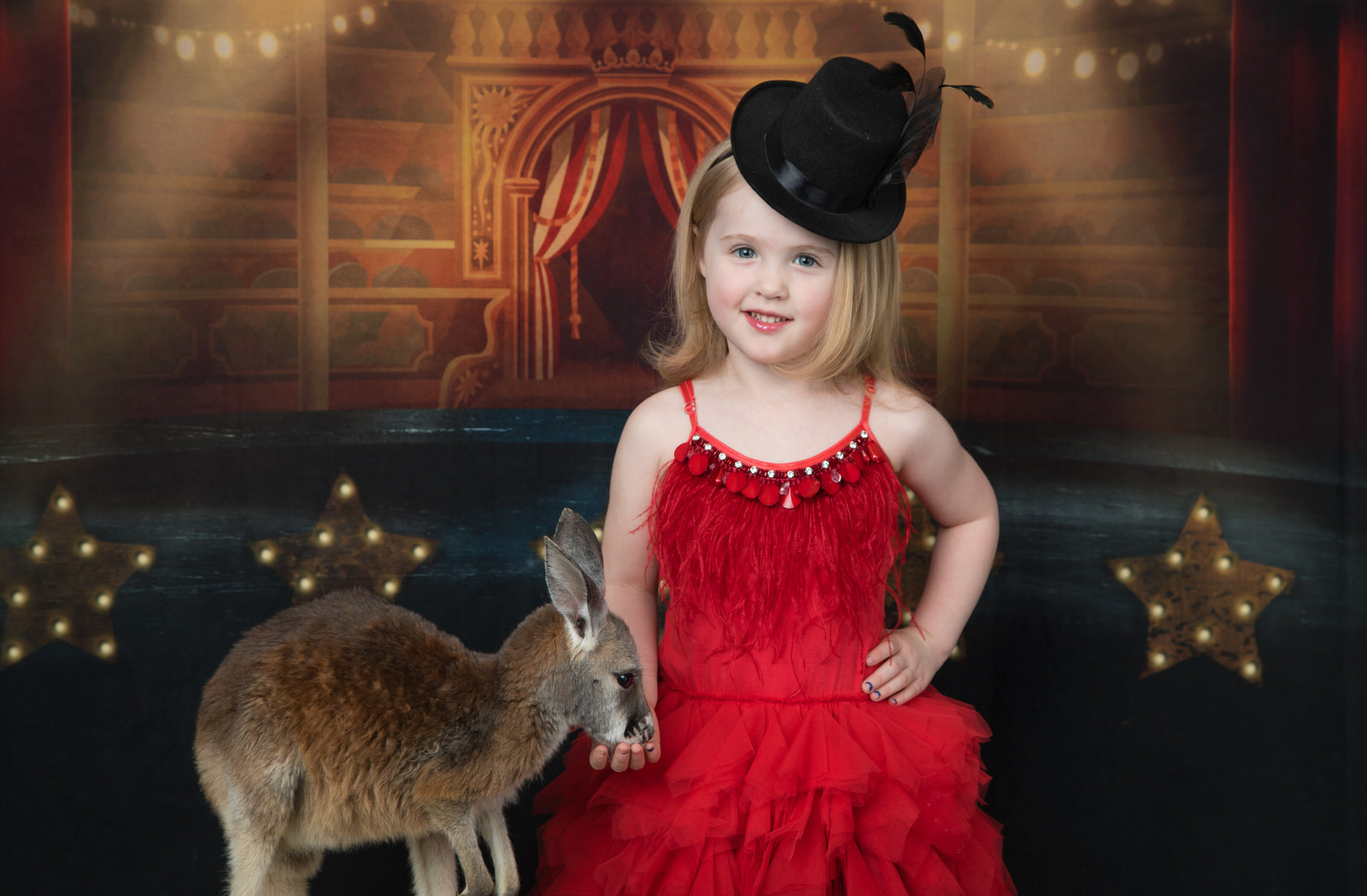 A young girl in a red flapper dress and black hat stands in a circus feeding a baby kangaroo toy stores arlington tx