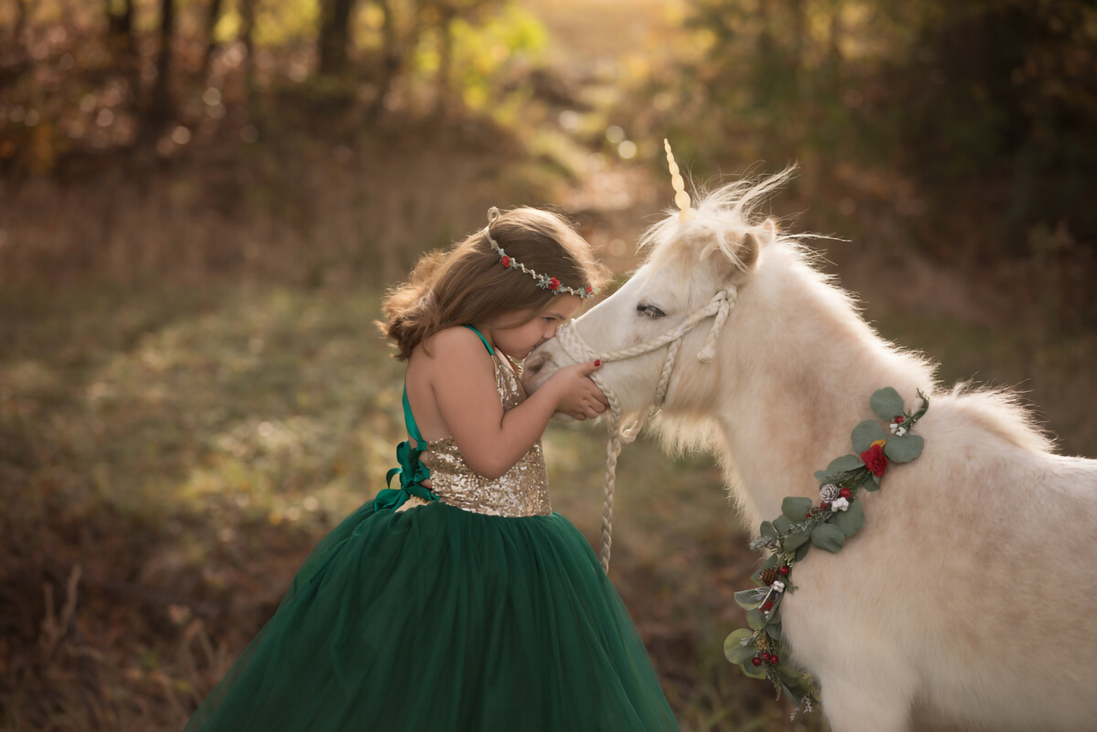 Girl in green holiday dress kissing unicorn