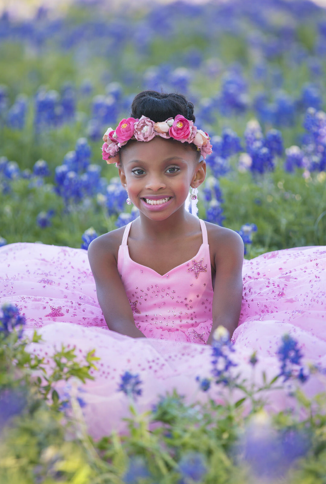 young girl in pink dress posing in field of bluebonnets