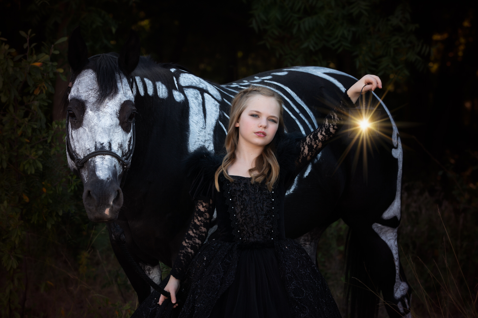 Girl in black dress holding lantern with skeleton horse