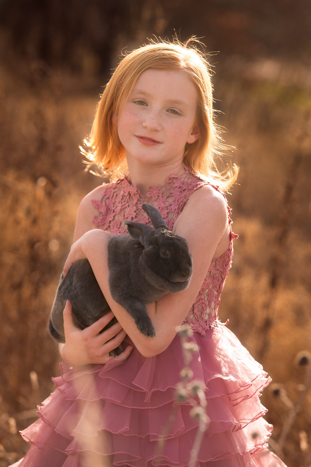 Girl holding bunny posing for spring bunny portrait session outdoors